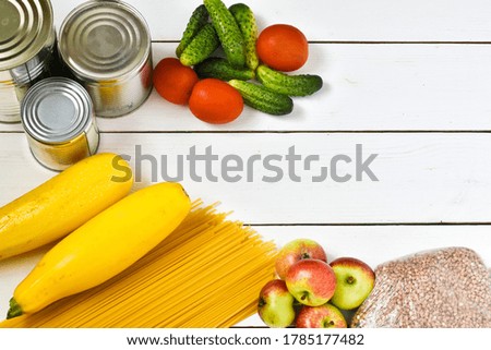 Food supplies.Food-Cucumbers, pasta, canned food, tomatoes on a wooden background. Food delivery, donation, coronavirus quarantine. Copy space.