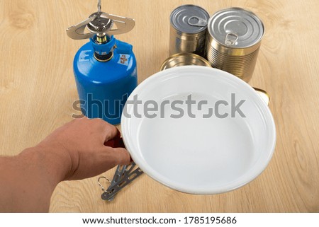 Picture of camping tools on a table -  gas tank, cans, etc - ready to go in the woods 