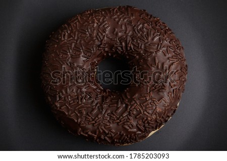 Chocolate donut on a black plate close-up.