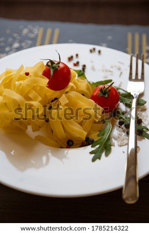 Tagliatelle and Cherry tomato served on white plate. Italian pasta knolling concept