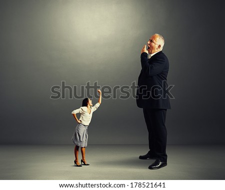 angry woman screaming at big yawning boss over dark background