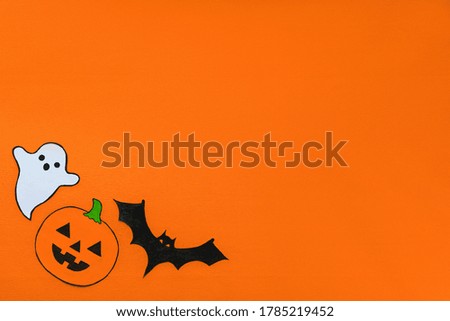 Carved scary figurines of ghost, pumpkin and bat on a yellow background, the concept of the holiday Halloween, space for text