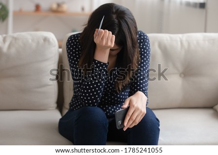 Distressed young woman hold cellphone and credit card frustrated by internet shopping failure or mistake. Unhappy girl have problem with online banking service system, cyber fraud. Scam concept Royalty-Free Stock Photo #1785241055
