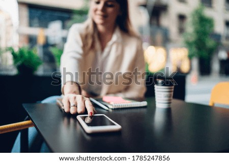 Blurred female user touching smartphone screen for checking received cellphone notification during leisure in city, millennial woman connecting to 4g wireless for installing application on mobile