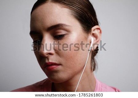 Side portrait of young woman with white small compact headphones. Space for text.