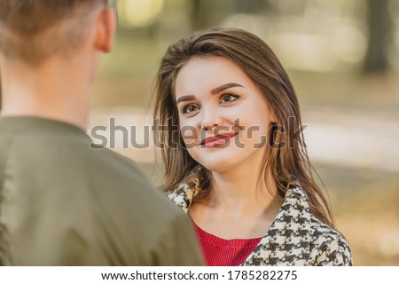 Adorable young woman is looking at her boyfriend, standing back to the camera, with big admiration and appreciation. Royalty-Free Stock Photo #1785282275