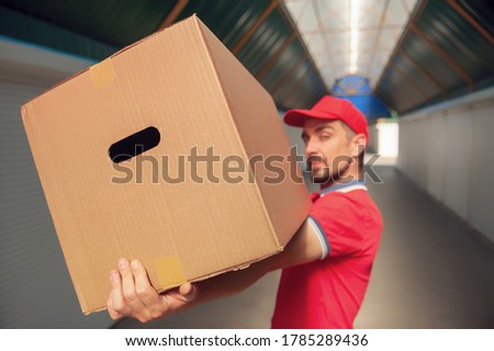 A man in a red suit in his hands with a cardboard box. Concept on the topic of postal delivery