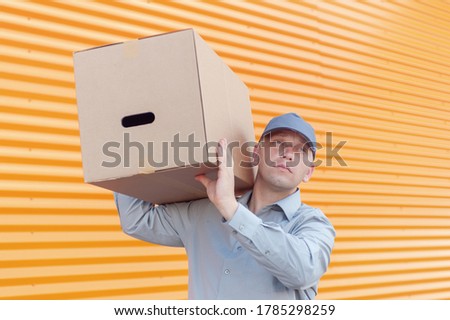 A man in a gray suit in his hands with a cardboard box. Concept on the topic of postal delivery