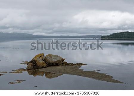 Rock reflection in the ocean on a cloudy day.
