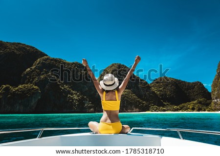 Travel summer vacation concept, Happy solo traveler asian woman with bikini and hat relax on boat in Maya Bay Phuket Thailand