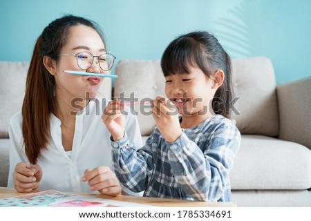  happy Asian family that has a mother and daughter sitting playing enjoying and activity together at home and sunlight morning 