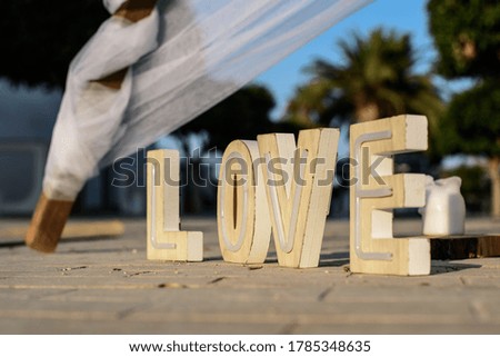 Wooden letters forming the word LOVE on the ground outdoors at an event.