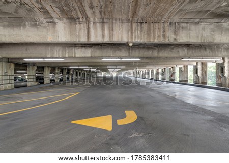 Empty parking garage with yellow lines for parking spaces and yellow directional arrows.