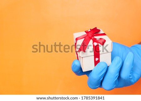 male hand in a blue medical glove gives a gift.