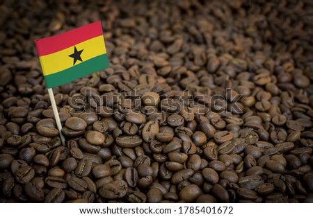 Ghana flag sticking in roasted coffee beans. The concept of export and import of coffee