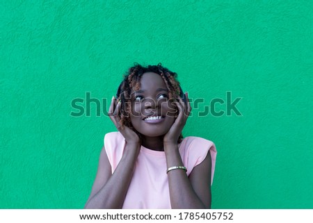the beautiful African American in headphones dancing, against a green background