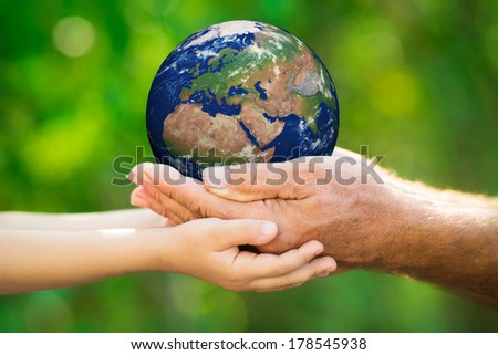 Child and senior man holding Earth in hands against green spring background. Elements of this image furnished by NASA