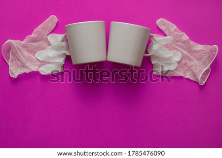 cheers with a cup of coffee. The picture shows coffee cups and the gloves on pink  background.