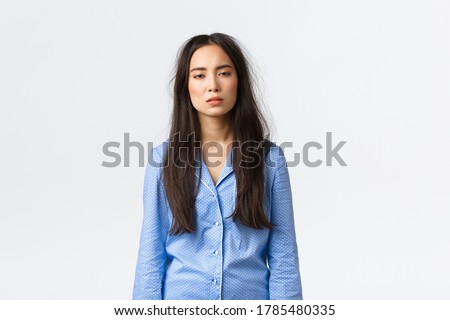 Exhausted asian woman with messy hair after lying in bed, wearing pajamas, looking tired with sleepy eyes as suffering insomnia, didnt have much sleep, waking up early, standing white background Royalty-Free Stock Photo #1785480335