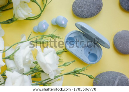 small real wireless headphones. blue earphones with stones, buds with  flowers. minimal. eustoma