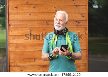Thoughtful senior sportsman using mobile phone
