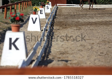 Sand covered equestrian horse arena close up white railing borders outdoors summertime