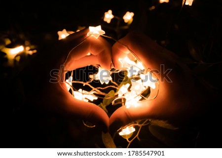 Led star shape light and hands in shape of love heart with dark background. Valentines day celebration.