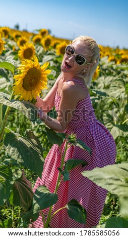 in sunflowers in a beautiful red dress in sunglasses, beautiful blonde in the heat of summer bright light Light haired