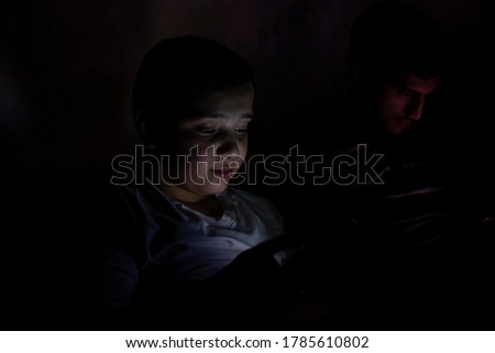 boys sitting in dark rooms on their smartphones using the internet
