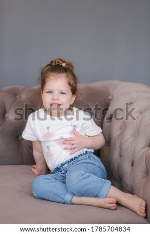 Portrait of beautiful little girl sits on sofa in studio