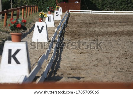 Sand covered equestrian horse arena close up white railing borders outdoors summertime