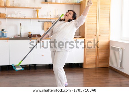 A fat, attractive woman cleans the house. She holds a MOP and sings a song.