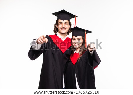 Two graduate couple pointed on camera isolated on white background