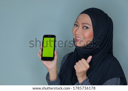 Smile asian woman holding smartphone with green screen. Selected focus on smartphone 