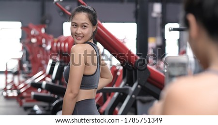 Sporty young asian women with friends taking picture of her friend using mobile phone, Females having fun in gym, Sportive fitness training exercise and healthy lifestyle concept.
