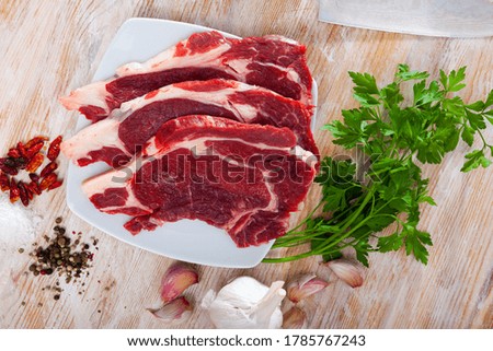 Close up of raw veal  on wooden surface with ingredients, nobody