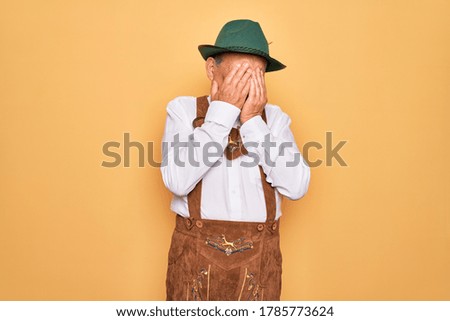 Senior grey-haired man wearing german traditional octoberfest suit over yellow background rubbing eyes for fatigue and headache, sleepy and tired expression. Vision problem