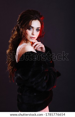 Beauty Fashion Model Girl in Mink Fur Coat. Beautiful Woman in Luxury Brown Fur Jacket . Winter Fashion Studio portrait of a caucasian well groomed brunette model posing on black background in studio