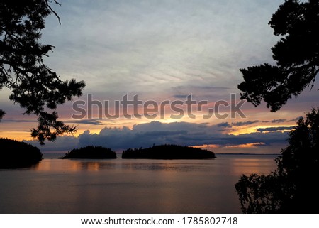 Beautiful sunset over islands in the lake, photo taken from the shore. Dramatic clouds over water, selective focus