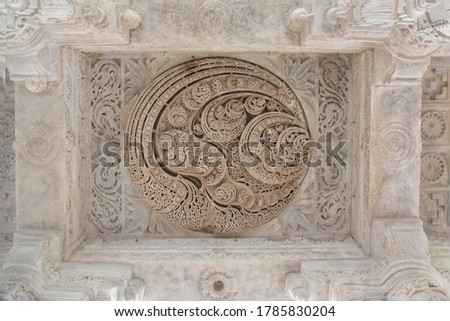 White pink marble stone carvings of ceiling of Jain temple mandir depicting religious murals in Ranakpur Chaumukha temple, Rajasthan, India Royalty-Free Stock Photo #1785830204