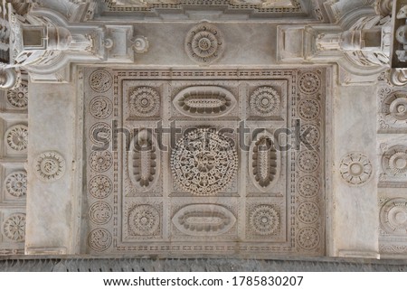 White pink marble stone carvings of ceiling of Jain temple mandir depicting religious murals in Ranakpur Chaumukha temple, Rajasthan, India Royalty-Free Stock Photo #1785830207