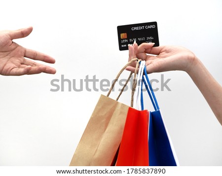 A picture of an isolate of a hand holding a black credit card and several paper bags  To submit payment to the other hand