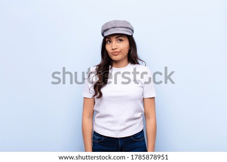 young latin pretty woman looking puzzled and confused, wondering or trying to solve a problem or thinking against flat wall