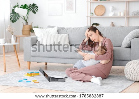Motherhood Exhaustion Concept. Tired young mom breastfeeding baby and working on laptop at home, feeling frustrated, free space Royalty-Free Stock Photo #1785882887