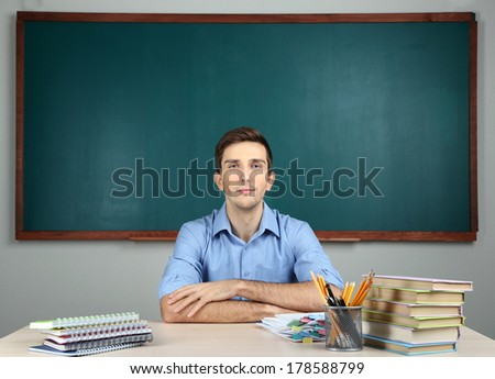 Young teacher sitting in school classroom