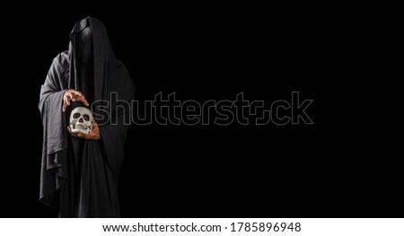 Portrait of a mysterious black man holding a skull in his hand isolated on black background