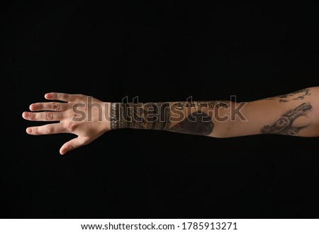 Woman with stylish tattoos on arm against black background, closeup