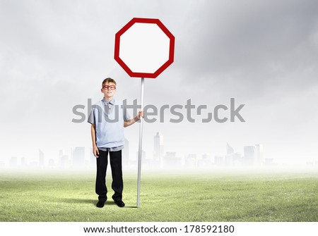 Boy of school age in glasses holding blank road sign