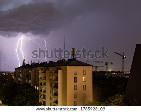 Violent summer thunderstorm with enormous lightning over the Wienerberg City in Vienna with construction cranes on the right side of the picture