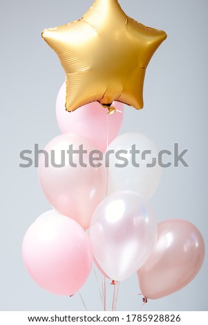 Composition of white, pink, transparent helium balloons and gold star on a white background.